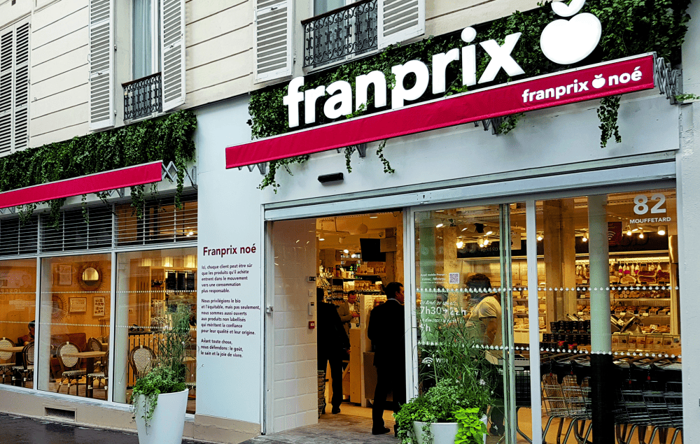Extérieur d'un magasin Franprix , avec façade blanche, plantes grimpantes.