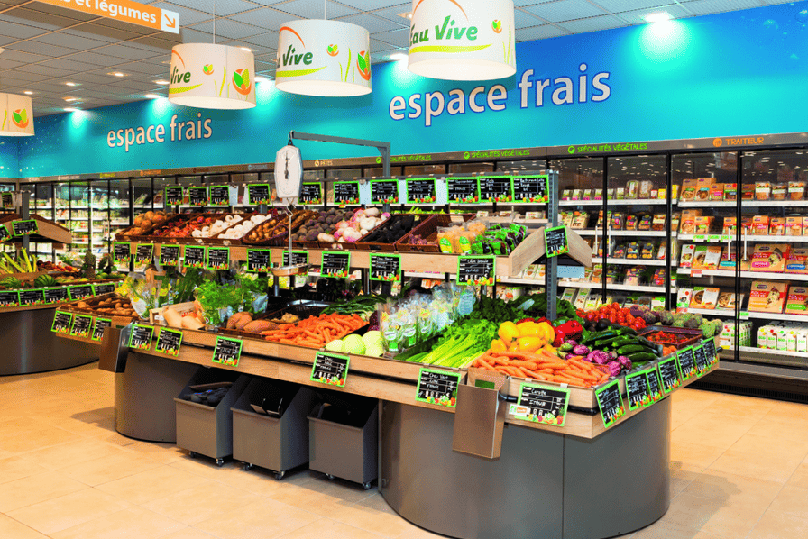 Rayon fruits et légumes frais avec carottes, poivrons et courgettes dans un magasin L'Eau Vive, espace frais.