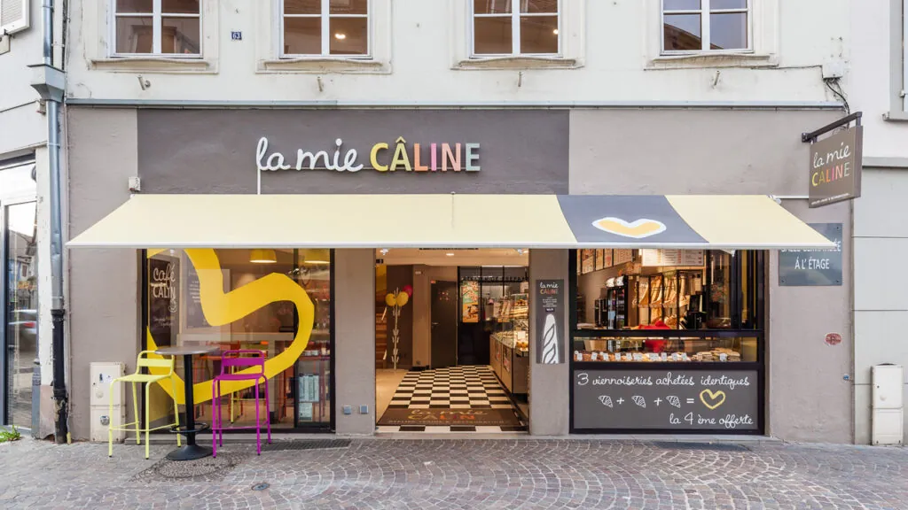 Devanture moderne de la boulangerie La Mie Câline avec sol en damier et offre promotionnelle sur les viennoiseries.