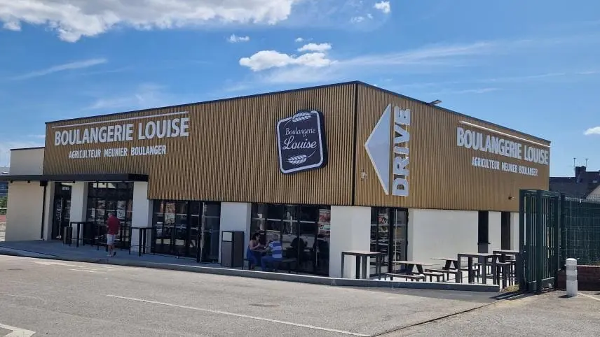 Façade extérieure de la Boulangerie Louise avec signalisation Drive et terrasse aménagée.