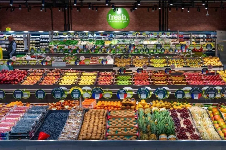 Rayon fruits et légumes frais de l'enseigne Fresh avec un large choix de produits colorés et bien rangés sur plusieurs niveaux.