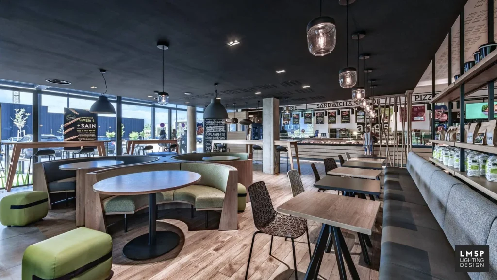 Intérieur design d'une boulangerie (Ange), espace de restauration avec canapés courbes, tables, chaises à motifs et luminaires suspendus.