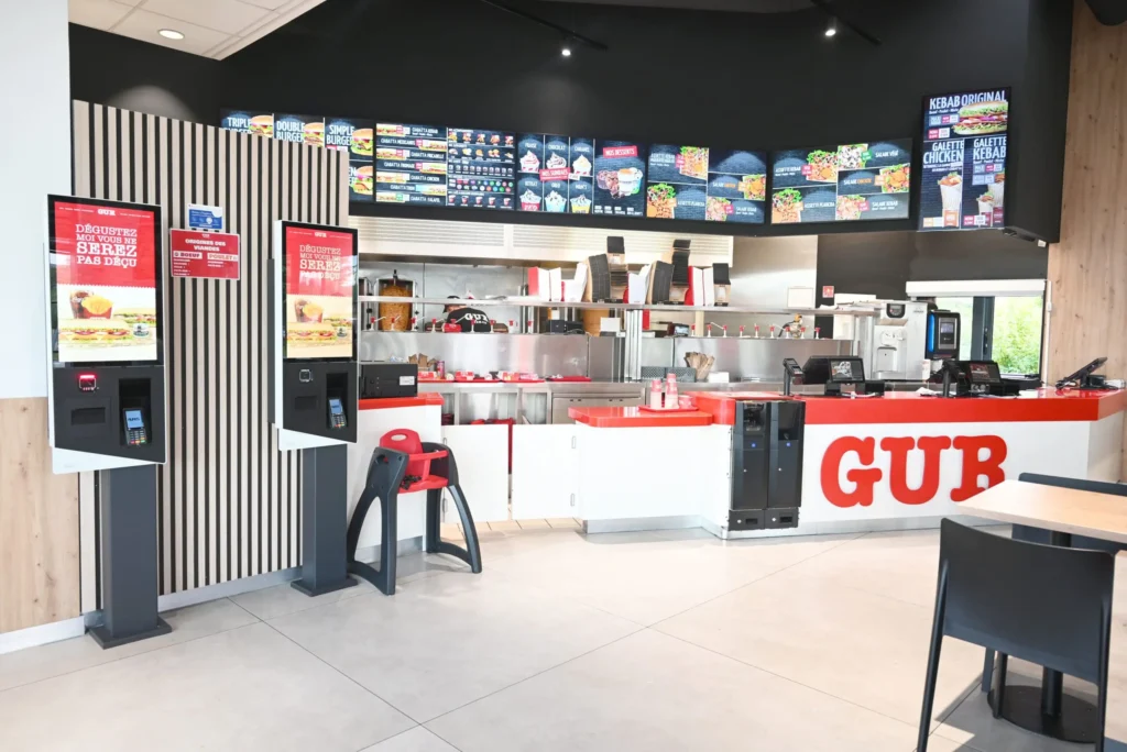 Comptoir intérieur d'un restaurant GUR Kebab avec bornes de commande tactiles.