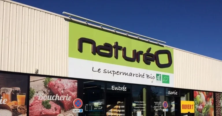 Entrée du supermarché bio Naturéo avec enseigne verte et blanche, affichages boucherie et logo Agriculture Biologique (AB).