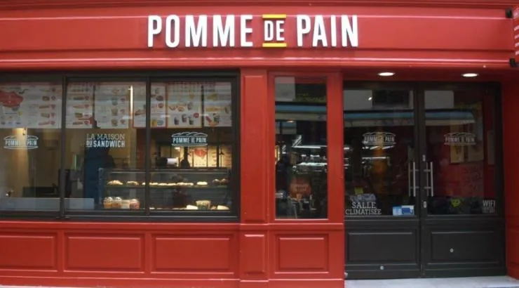 Devanture rouge vif d'un restaurant Pomme de Pain avec vitrine affichant les menus et mention salle climatisée.