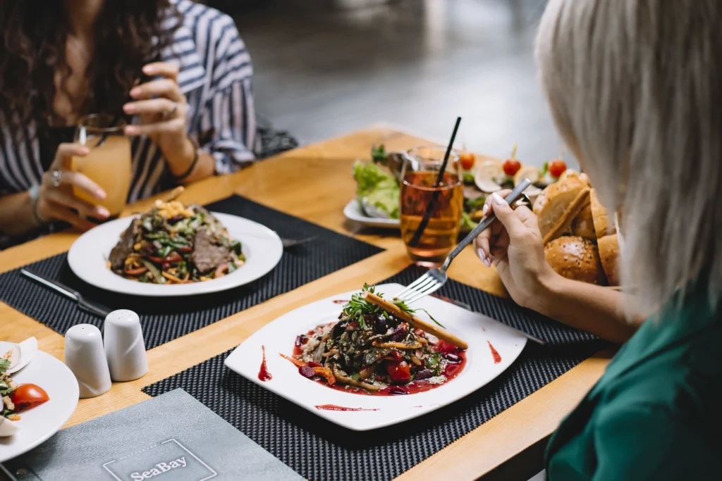 Gros plan sur une femme dégustant une salade composée colorée, illustrant comment manger sans gluten au restaurant en choisissant des plats à base de légumes frais.