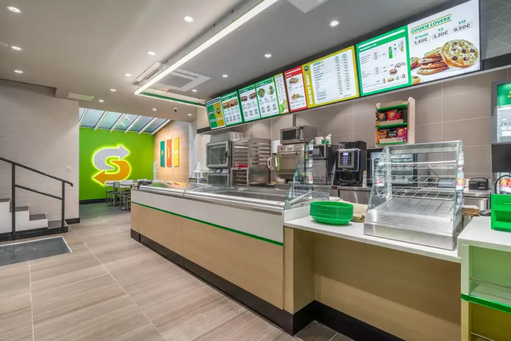 Comptoir de service et intérieur moderne d'un restaurant Subway avec menu affiché au mur.