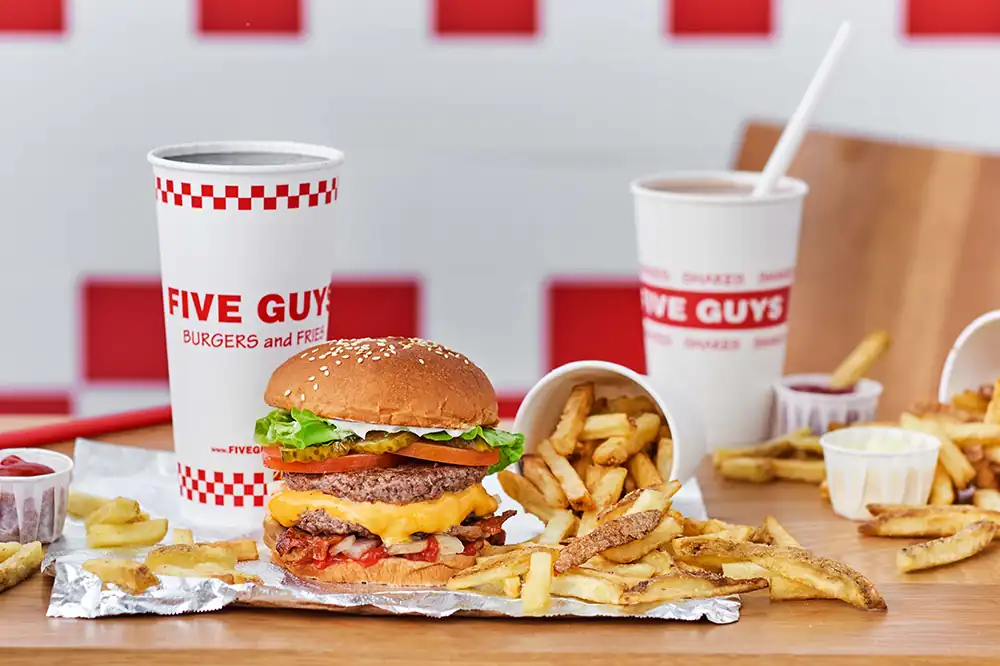 Menu complet Five Guys avec cheeseburger double, frites fraîches et boissons sur table