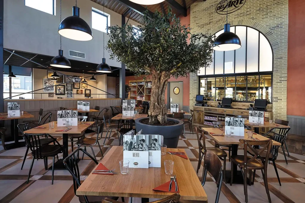 Intérieur chaleureux et décoration moderne d'un restaurant italien Del Arte avec olivier central.